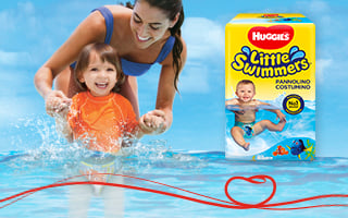 Mamma e figlio che giocano e ridono in acqua con Huggies® Little Swimmers