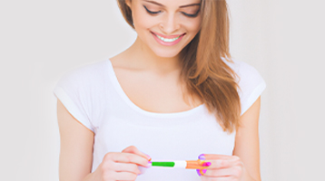 Smiling woman looking down at a pregnancy test